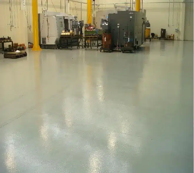 Engineering workshop concrete floor with a high gloss grey epoxy coating reflecting overhead machinery