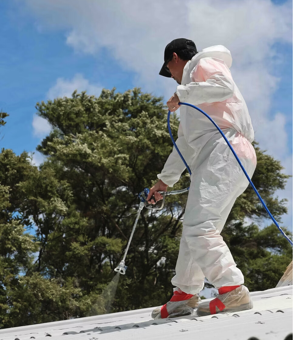 Professional applicator applying a protective roof coating to a corrugated roof
