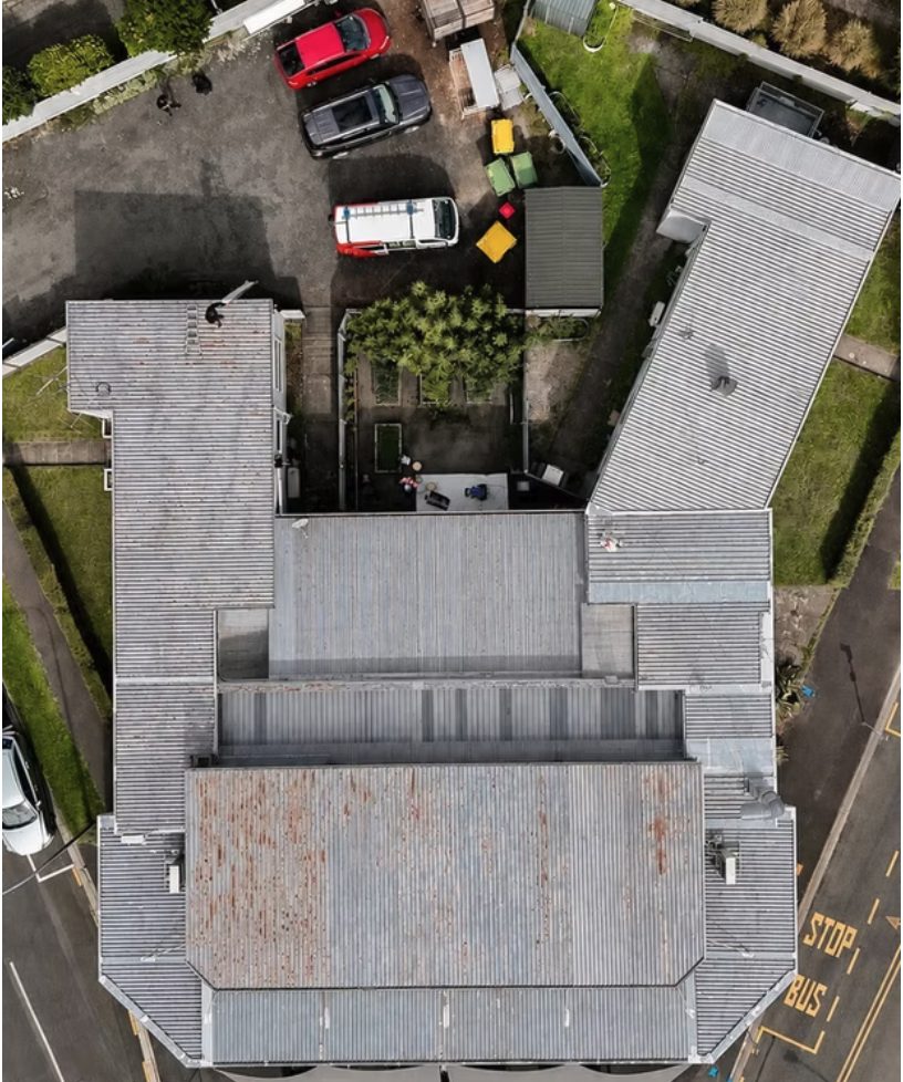 Aerial view of the weathered standing seam metal roof before coating, showing early corrosion