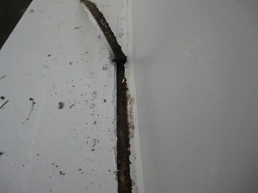 Corroded, split joint between a steel silo and its concrete plinth before treatment
