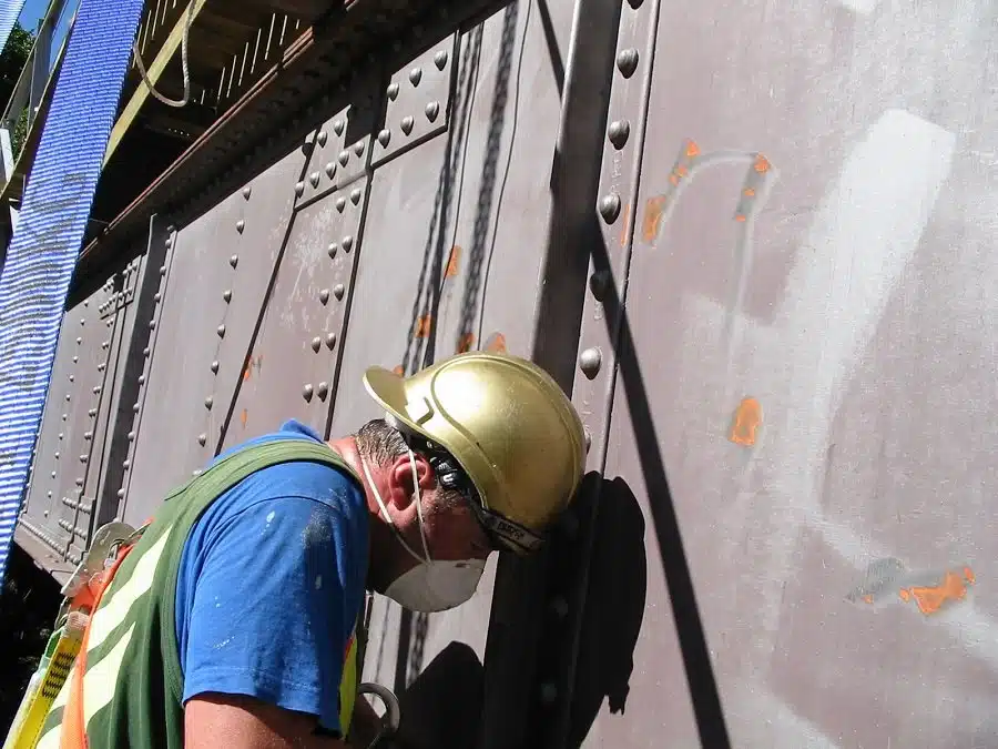 Applicator preparing the corroded steelwork of the Hapuawhenua Viaduct before coating