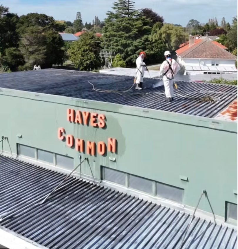 Applicators in protective suits spraying Noxyde onto the Hayes Common roof